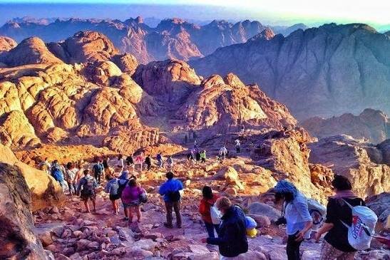 Hikers walking down the rocky path from the summit of Mount Sinai in the morning light