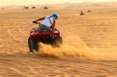 Quad bike rider kicking up sand on a desert dune