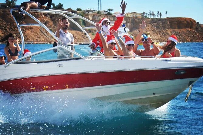 Gruppe mit Weihnachtsmützen winkt von einem Speedboot, das an der Küste von Sharm El Sheikh entlangfährt