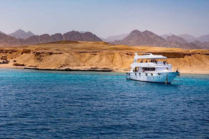 White boat anchored in turquoise Red Sea waters near Ras Mohamed with desert mountains behind
