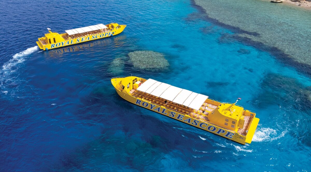 Two yellow Royal Seascope semi-submarines cruising over coral reefs in turquoise water, seen from above