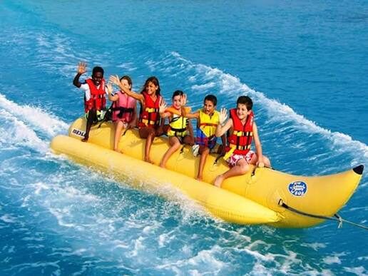 Enfants en gilet de sauvetage saluant sur une bouée banane jaune sur une eau turquoise